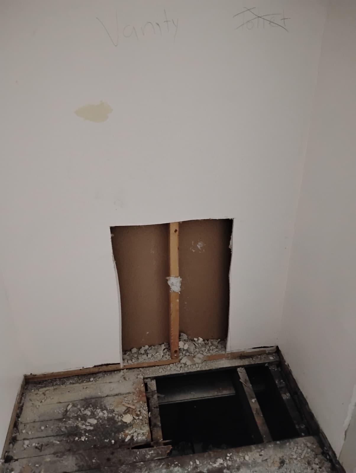 Wall opened for plumbing access behind the vanity